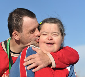 Man kissing happy girl with special needs on the cheek.